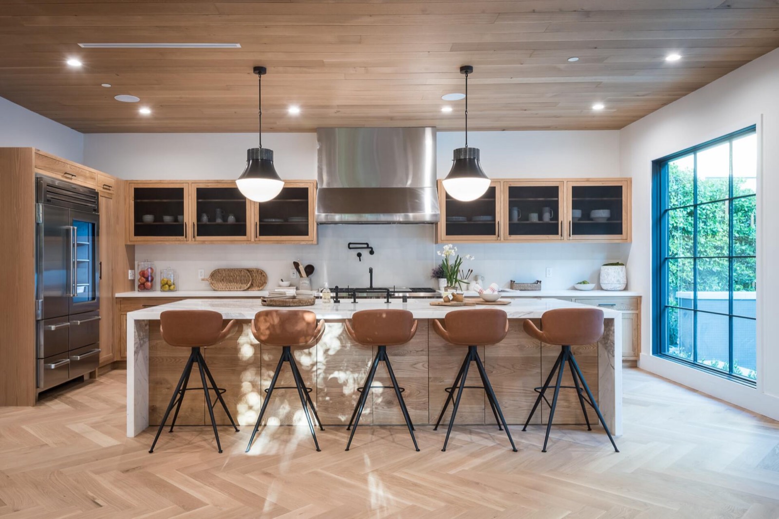 Cuisine rénovée avec îlot en bois, plancher à chevrons et grandes fenêtres